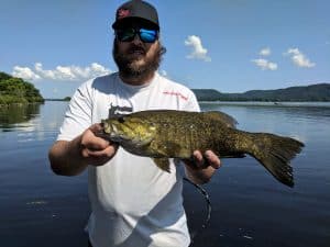 Smallmouth bass recently caught on river riverbank in background
