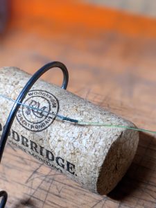 how to tie an alberto knot with braided line connected to mono line. Fishing hook point in cork with alberto knot being shown