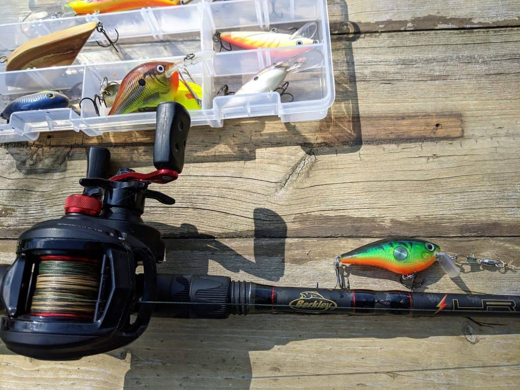 several crankbaits for bass fishing in tacklebox with crankbait tied on to fishing rod with abu garcia baitcaster reel