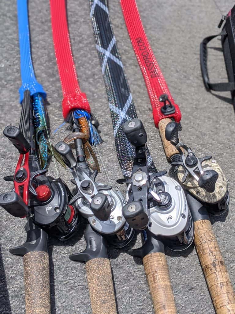 Several baitcaster reels and rods lined up on a boat deck