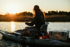 fishing is good for mental health. man fishing on a kayak at sunrise