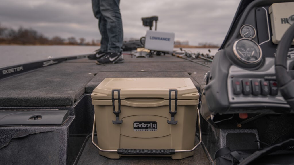 grizzly boat cooler sitting closed just before bow of boat with angler casting
