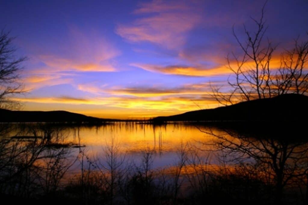 Sardis Lake at sunset with very beautiful colors streaming through the evening sky and wispy clouds. One of the underrated best bass fishing lakes in Mississippi